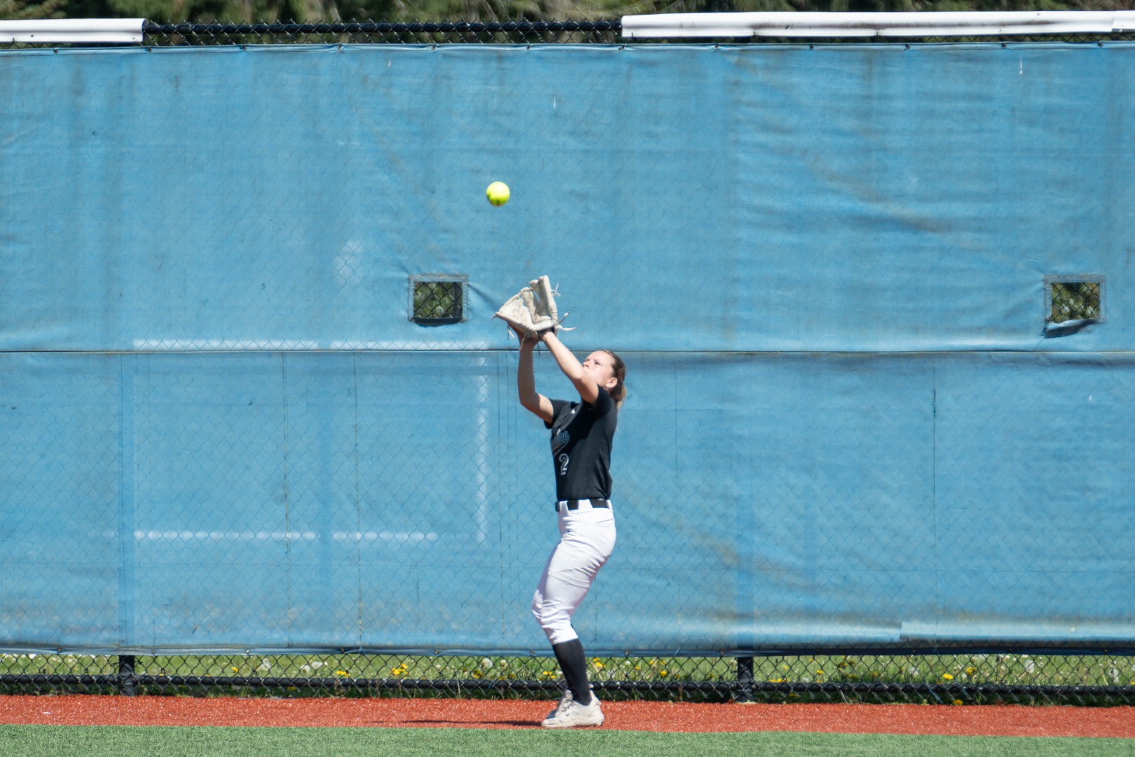 Shoreline softball outfielder tracking a fly ball in front of the fence