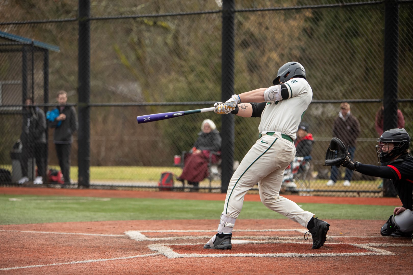 Shoreline batter finishing his swing against the fence backdrop